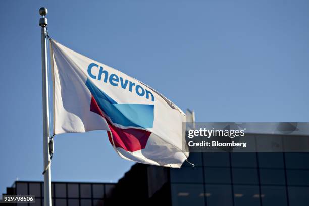 Chevron Corp. Flag flies outside an office building in Midland, Texas, U.S., on Thursday, March 1, 2018. Chevron, the world's third-largest publicly...