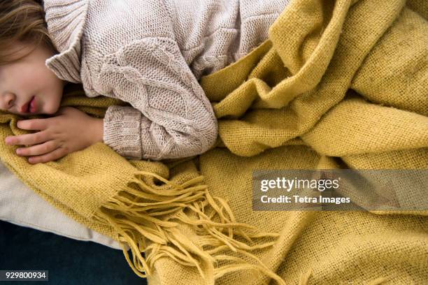 girl (4-5) lying on sofa covered with blanket - blanket stock-fotos und bilder