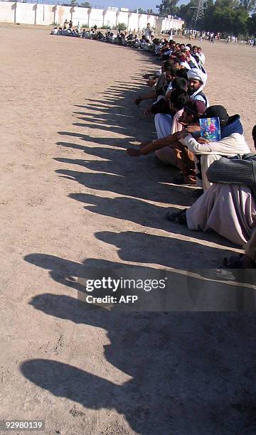 Internally displaced Pakistani tribesmen, fleeing from military operations against Taliban militants in South Waziristan, sit in a queue as they wait...