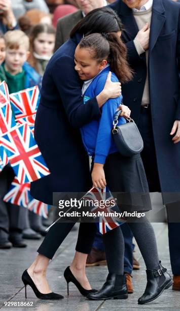Meghan Markle hugs a young girl during a walkabout at Millennium Point before attending an event to celebrate International Women's Day on March 8,...