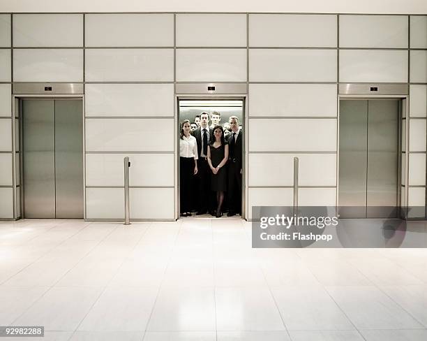 group of business people inside an office lift - crowded elevator stockfoto's en -beelden