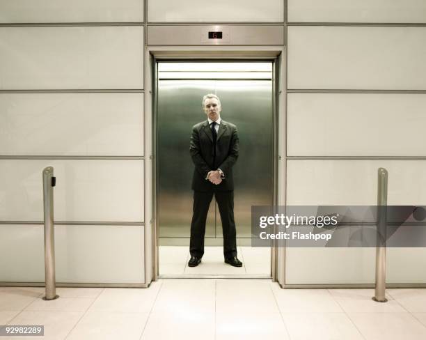 businessman standing in office lift - ascensor fotografías e imágenes de stock
