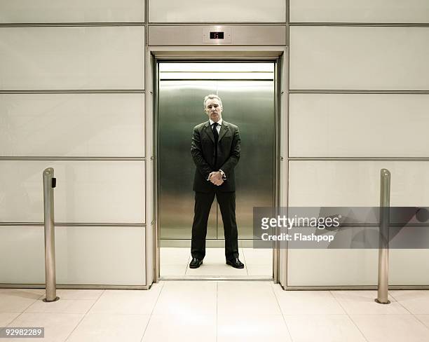 businessman standing in office lift - ascenseur interieur photos et images de collection