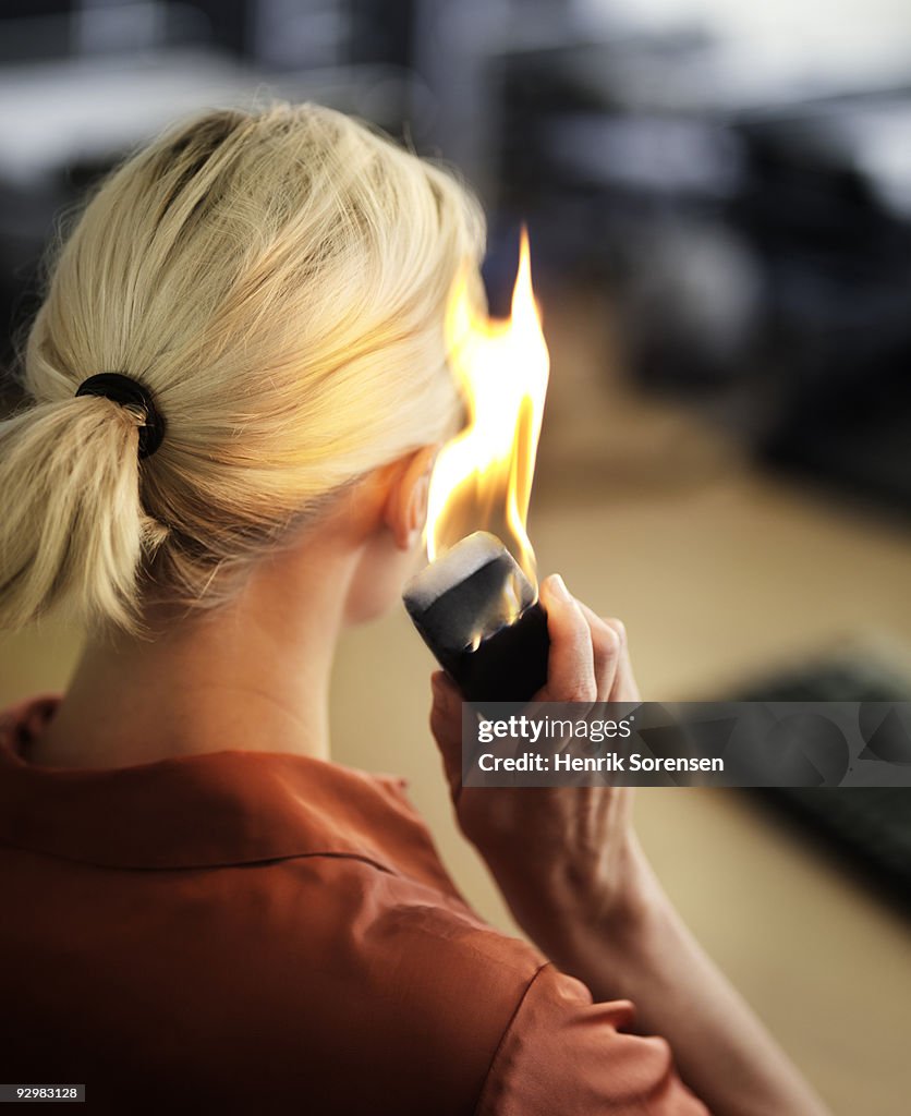 Businesswoman talking on flaming mobile phone