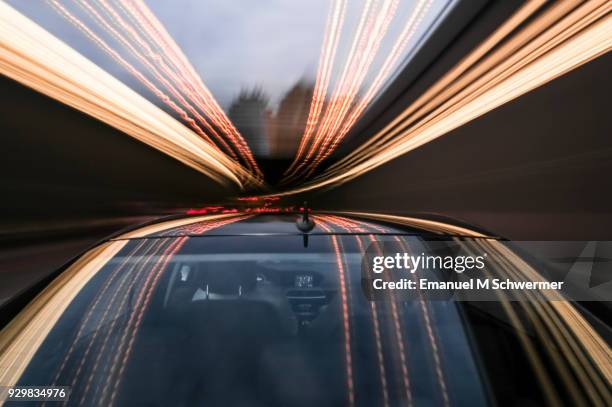 driving black german car with reflections and the rear window in foreground - copper tunnel stock pictures, royalty-free photos & images