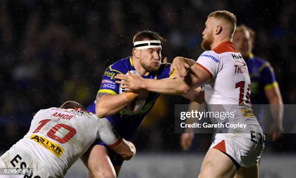 Mike Cooper of Warrington is tackled by Kyle Amor and Luke Thompson of St Helens during the Betfred Super League between Warrington Wolves and St...