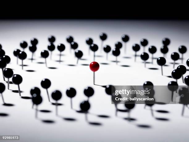 circle of black push pins surrounding red pin. - push pin fotografías e imágenes de stock