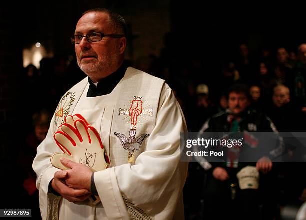 Catholic priest Heinrich Plochg holds the signed goalkeeper gloves of Germany's late national goalkeeper Robert Enke during a mourning service at the...