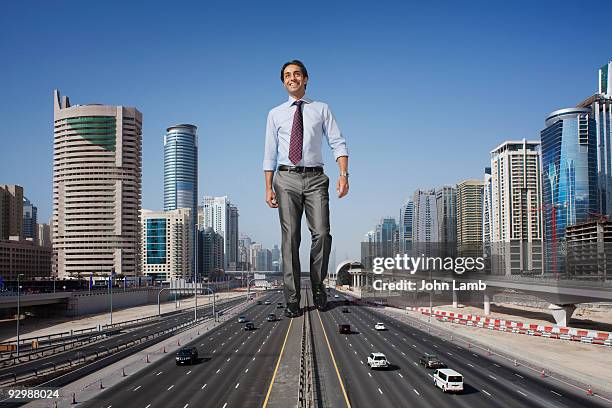 big giant businessman walking in dubai - groot stockfoto's en -beelden