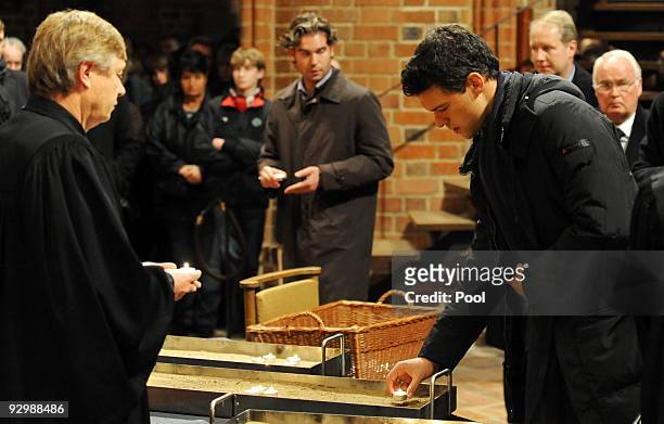 Michael Ballack lights a candle during a church service for German national goalkeeper Robert Enke at the 'Marktkirche' on November 11, 2009 in...
