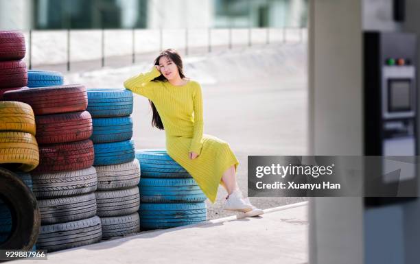 portrait of young woman sitting by the tires - long bright yellow dress stock pictures, royalty-free photos & images