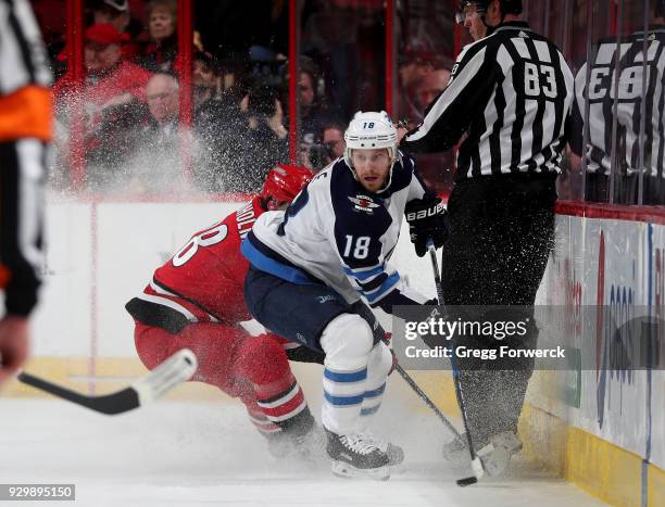 Bryan Little of the Winnipeg Jets gains control of a puck along the boards away from the defense of Elias Lindholm during an NHL game on March 4,...