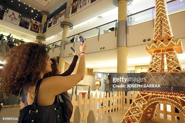 Young Lebanese women take pictures with their mobile phones of a matchstick model of the tallest Eiffel Tower, constructed by wheelchair-bound...