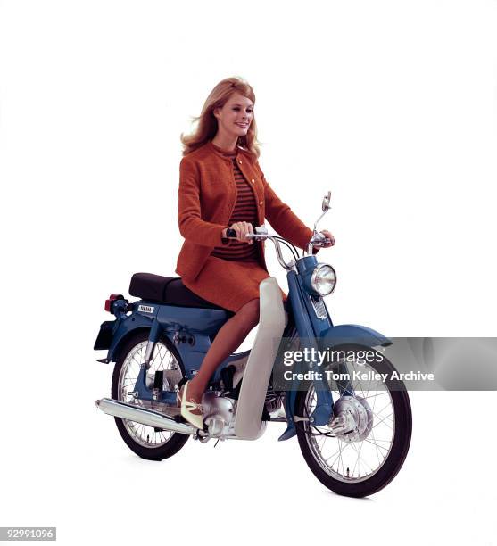 Woman smiles while riding a 1966 Yamaha scooter.