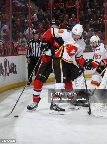 Matthew Tkachuk of the Calgary Flames battles for puck possession behind the net against Cody Ceci of the Ottawa Senators at Canadian Tire Centre on...