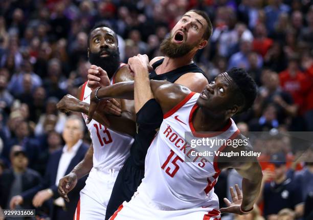 Jonas Valanciunas of the Toronto Raptors battles for a rebound with James Harden and Clint Capela of the Houston Rockets during the second half of an...