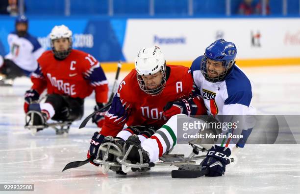 Knut Andre Nordstoga of Norway battles for the puck with Sandro Kalegaris of Italy in the Ice Hockey Preliminary Round - Group A game between Norway...