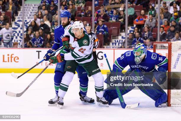 Minnesota Wild Right Wing Nino Niederreiter stands in front of Defenceman Erik Gudbranson and Vancouver Canucks Goalie Anders Nilsson during their...