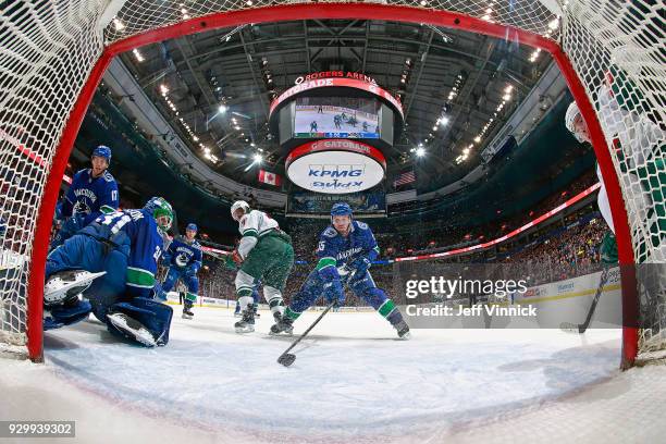 Matt Cullen of the Minnesota Wild looks on as Alex Biega of the Vancouver Canucks blocks a shot during their NHL game at Rogers Arena March 9, 2018...