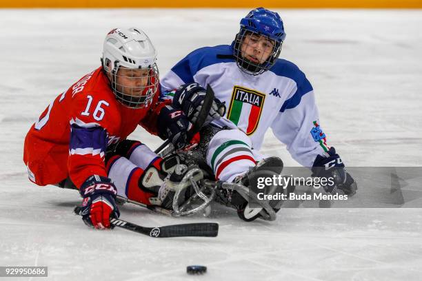 Knut Andre Nordstoga of Norway battles for the puck with Christoph Depaoli of Italy in the Ice Hockey Preliminary Round - Group A game between Norway...