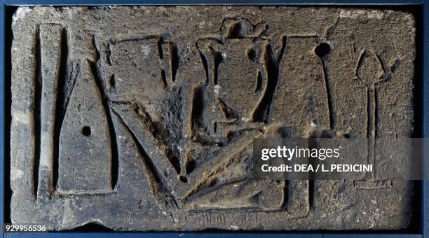 Tuff relief with a set of construction work tools: plumb bob, trowel, plumb line, pick, chisel, amphora and smashing tool and an auspicious phallus...