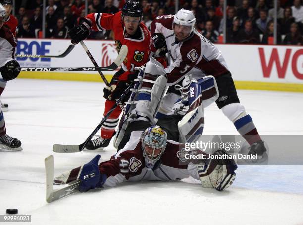 Craig Anderson of the Colorado Avalance sprawls to make a save as teammate Brett Clark battles with Andrew Ebbett of the Chicago Blackhawks at the...