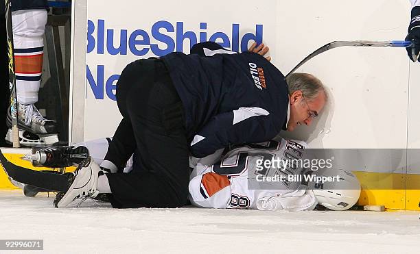 Head medical trainer Ken Lowe tends to Liam Reddox of the Edmonton Oilers after he was injured from a third period check into the boards by Clarke...