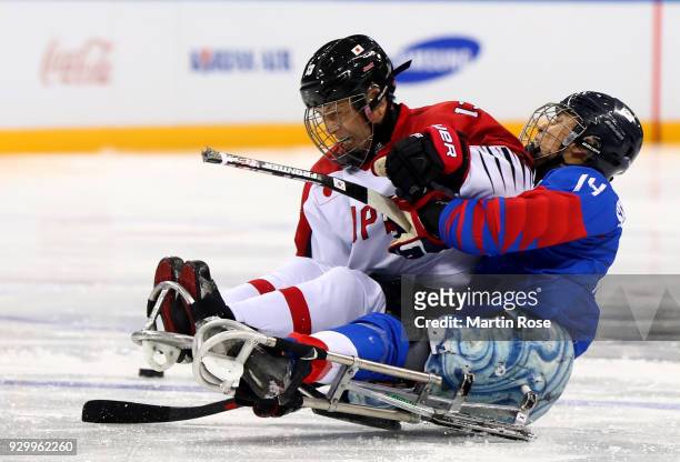 Seung Hawn Jung of Korea battles for the puck with Mamoru Yoshikawa of Japan in the Ice Hockey Preliminary Round - Group A game between South Korea...