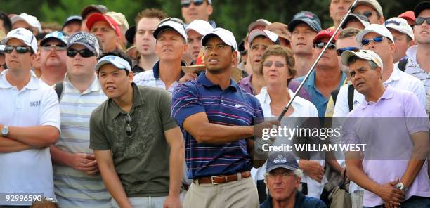 Spectators crane look on as Tiger Woods of the US watches the flight of the ball during the first round of the Australian Masters golf tournament at...