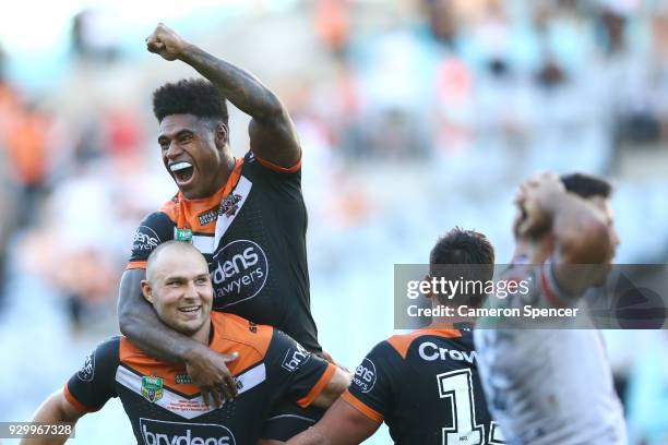 Kevin Naiqama of the Tigers celebrates on the shoulders of team mate Robert Rochow after winning the round one NRL match between the Wests Tigers and...