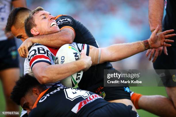 Mitchell Aubusson of the Roosters is tackled by Luke Brooks and Kevin Naiqama of the Tigers during the round one NRL match between the Wests Tigers...