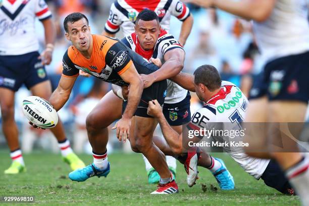 Corey Thompson of the Tigers passes as he is tackled during the round one NRL match between the Wests Tigers and the Sydney Roosters at ANZ Stadium...