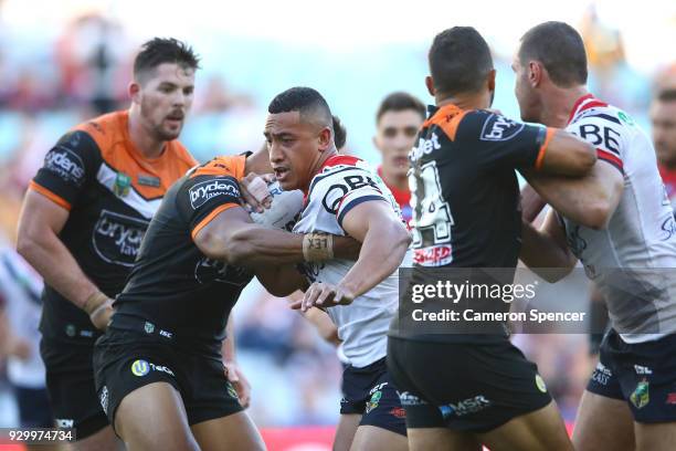 Sio Siua Taukeiaho of the Roosters is tackled during the round one NRL match between the Wests Tigers and the Sydney Roosters at ANZ Stadium on March...