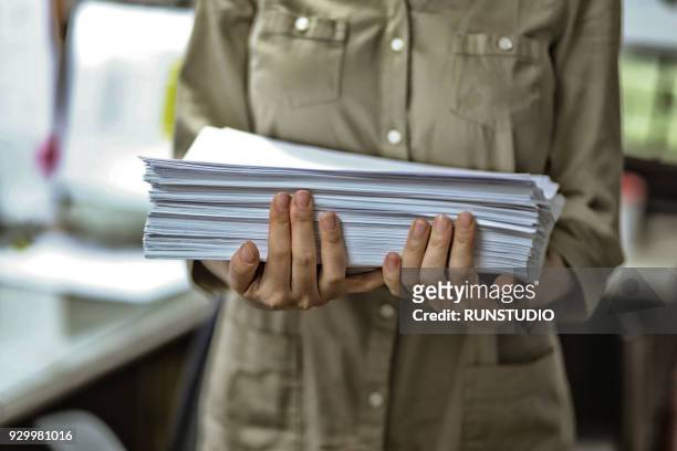 businesswoman holding stack of documents in office - frau aktenordner stock-fotos und bilder