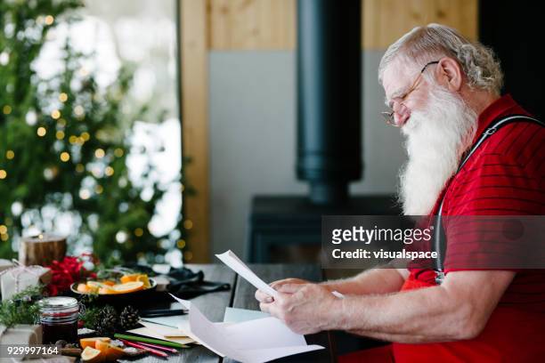 santa claus smiling while reading children's letters - santa beard stock pictures, royalty-free photos & images