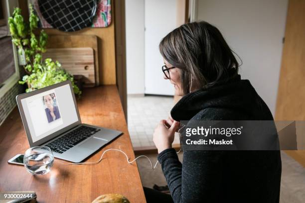 Side view of businesswoman video calling female colleague on laptop in home office