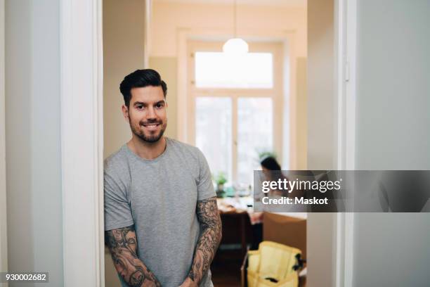 portrait of smiling man leaning on doorway at new home - doorway stockfoto's en -beelden