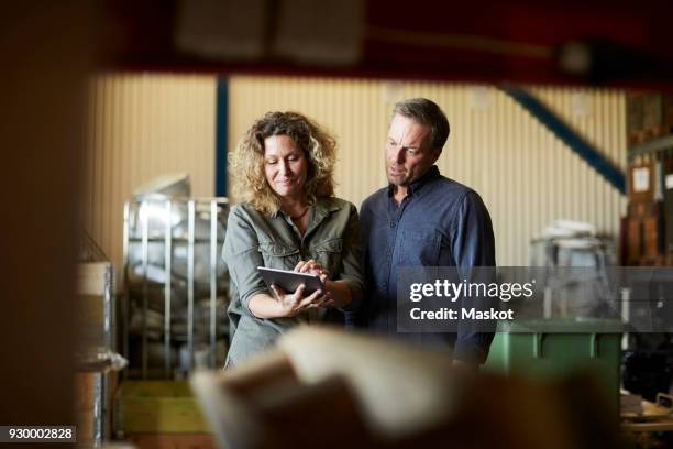 mature colleagues discussing over digital tablet seen through rack at warehouse - tool rack ストックフォトと画像