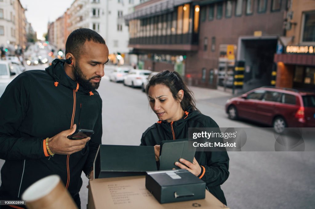 Serious coworkers talking while using technologies in delivery van at city