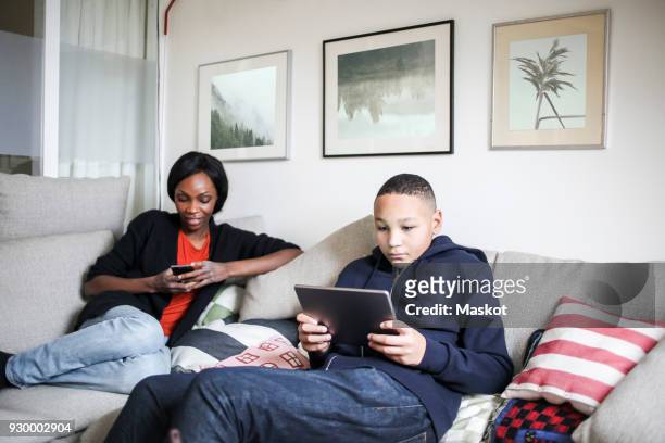 mother and son using technologies on sofa at home - pillow icon stock pictures, royalty-free photos & images
