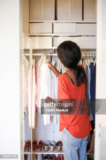 rear view of woman arranging wardrobe at home - tidy room stock pictures, royalty-free photos & images