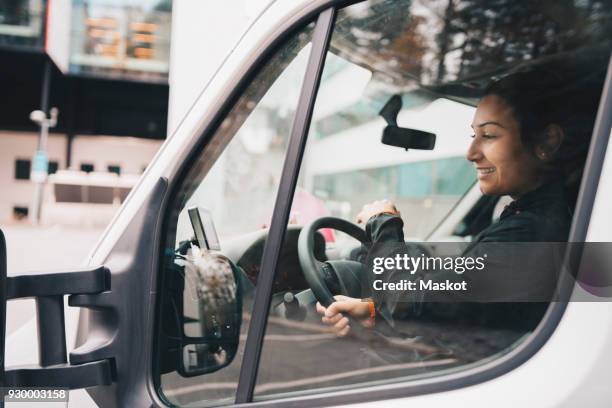 smiling woman driving delivery van in city - nutzfahrzeug stock-fotos und bilder