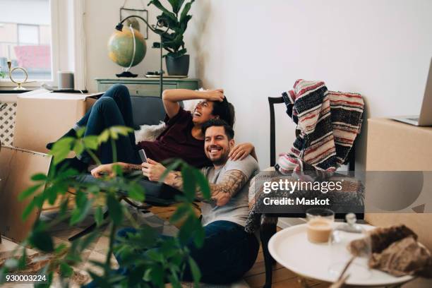 happy couple using smart phone while resting at new home during location - ouder-volwassenen-koppel stockfoto's en -beelden