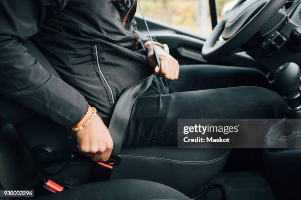 midsection of male worker sitting in delivery van - seat belt stock-fotos und bilder
