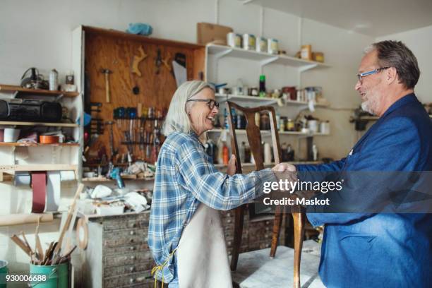 senior owner shaking hands with customer while selling wooden chair at workshop - antiquario foto e immagini stock