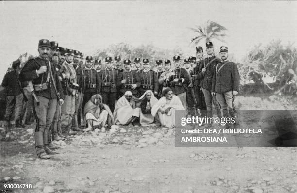 Italian soldiers with four Arab traitors condemned to death, Derna, Libya, Italian-Turkish war, photograph by Del Sacco, from L'Illustrazione...