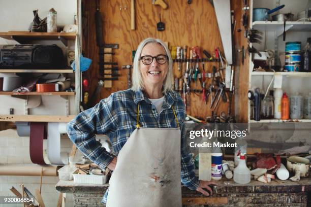 portrait of smiling senior owner standing against tools at workshop - large group of craftsman stock-fotos und bilder