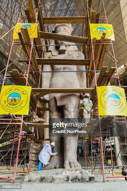 Egyptian workers restore a giant granite statue of the ancient Egyptian Pharaoh Ramses II at the Atrium of the Grand Egyptian Museum , near the...