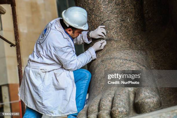 Egyptian workers restore a giant granite statue of the ancient Egyptian Pharaoh Ramses II at the Atrium of the Grand Egyptian Museum , near the...