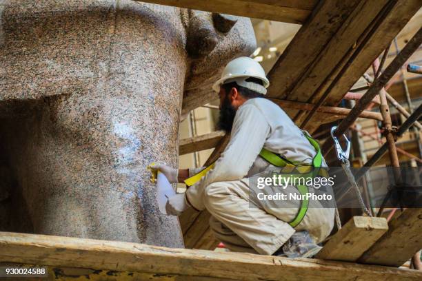 Egyptian workers restore a giant granite statue of the ancient Egyptian Pharaoh Ramses II at the Atrium of the Grand Egyptian Museum , near the...